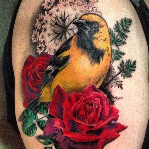 A yellow oriole poses with roses in this girly floral tattoo by Butterfat studios