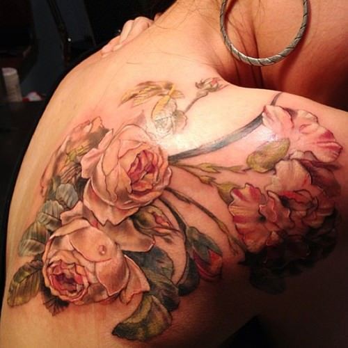The pink feminine roses in this feminine tattoo have an antique design style that is a perfect choice for elegant women
