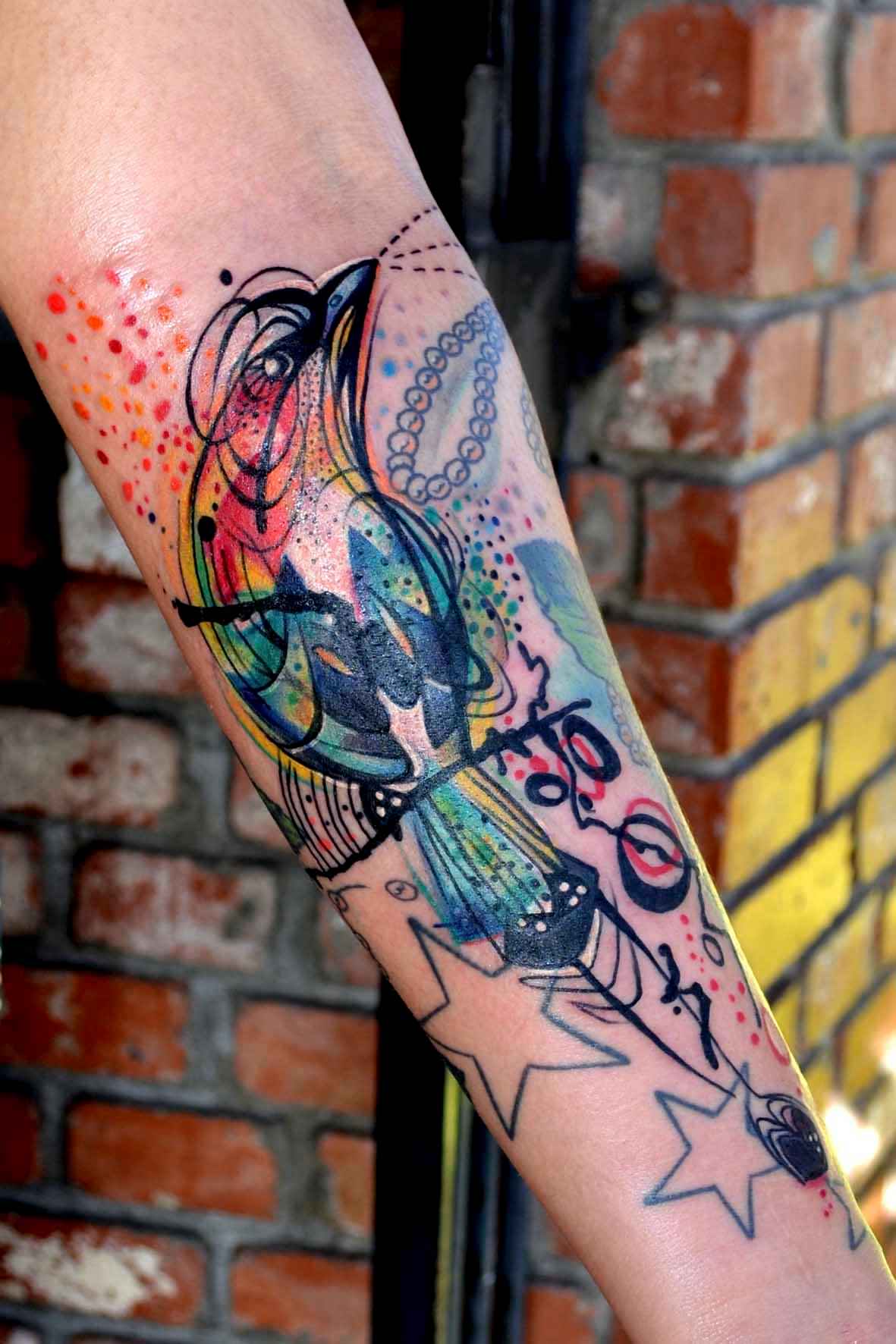 This colorful bird tattoo by Petra works a charm to pull together the