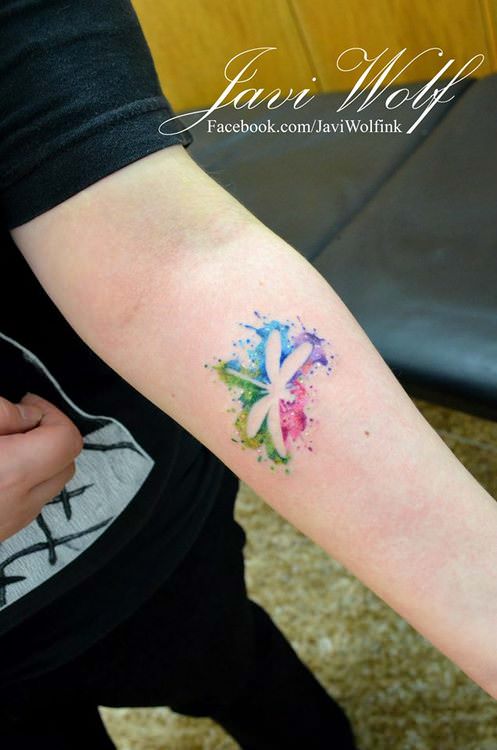 Javi Wolf creates a silhouette of a dragonfly in this colorful artistic tattoo
