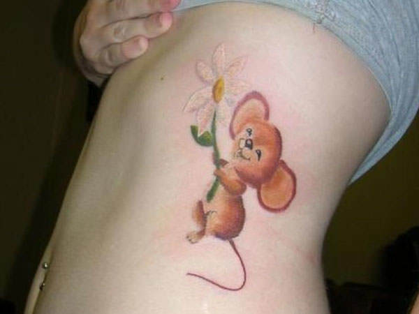 A cute little mouse holds a flower while skipping happily in this fun and innocent tattoo