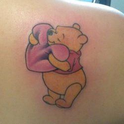 Cuddly and courageous, the friendly Pooh Bear hugs a heart in this cute and lovable tattoo design