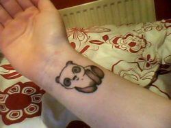 Simply adorable! A cute little panda looks out of this wrist tattoo design