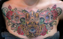 This Hamsa hand tattoo has a distinct Mexican flavor with its sugar skulls and roses