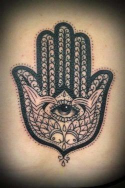 This Hamsa hand tattoo includes fish as symbols of abundance