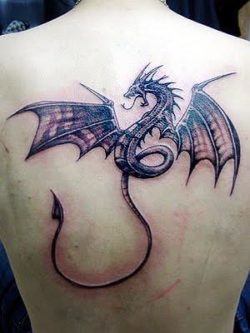 A black and grey tattoo dragon spreads its wings across the shoulders of its wearer