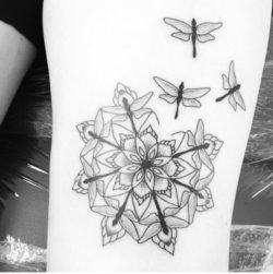 Dragonflies form a mandala shape around a flower in this spiritual nature tattoo