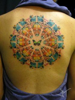 This colorful mandala tattoo uses butterfly wings to create the form of the sacred geometry, symbolizing flight, freedom, spirituality and beauty