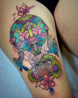 A beautifully detailed hot air balloon carries an antique suitcase in this bright color watercolor tattoo by Katie Shocrylas