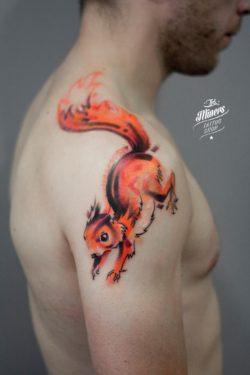 A bright orange watercolour squirrel leaps across this guy's shoulder in this artistic tattoo by Magda from Ink Miners