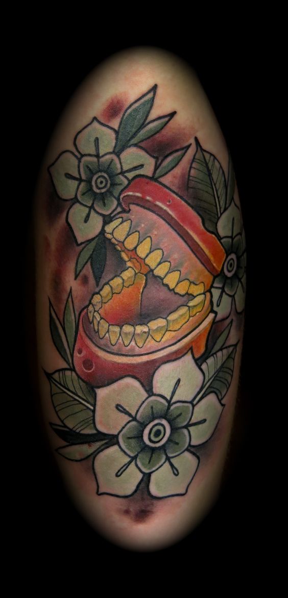 A pair of dentures cackle away at the centre of this funny tattoo by Rodrigo Kalaka