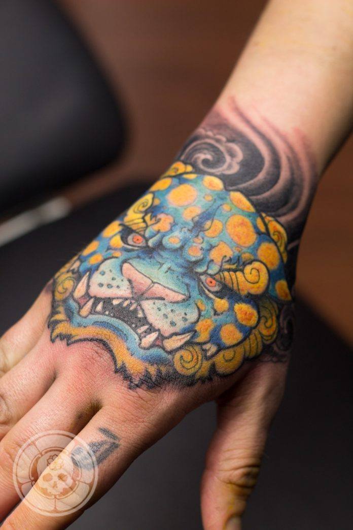 Ben Shaw tattoos a fierce Foo Dog in bright blues and yellows.