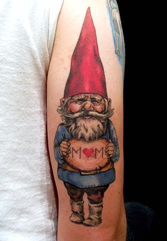 A gnome holds up a sign that says MOM in this cute tattoo