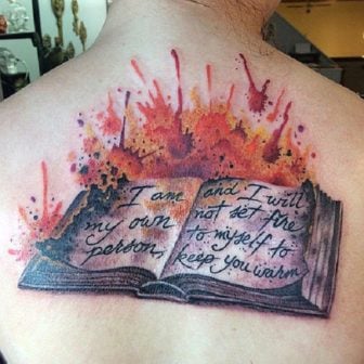 The words on the pages of this artistic book tattoo read, I am my own person and I will not set fire to myself to keep you warm.