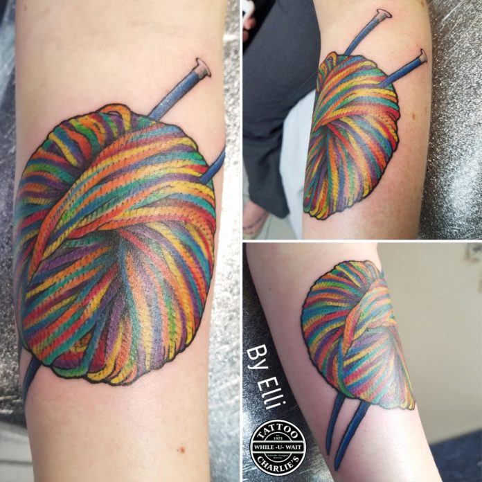 A knitting fanatic received this colorful tattoo of a ball of rainbow yarn with knitting needles poked through from tattoo artist Elli