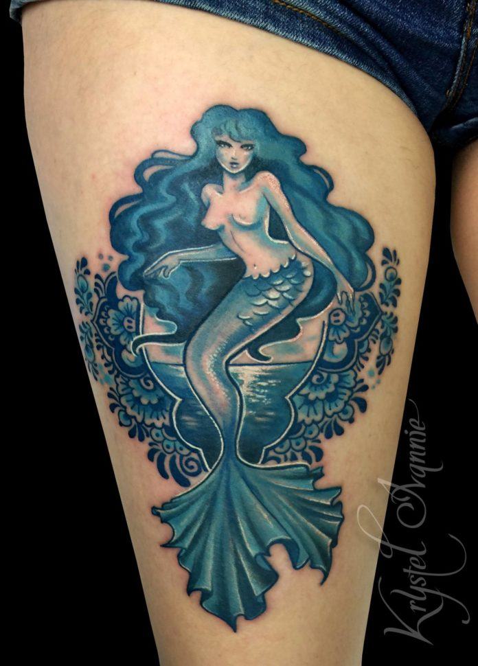 Decorative Delft Blue flowers frame a beautiful mermaid in this tattoo by Krystel Ivannie
