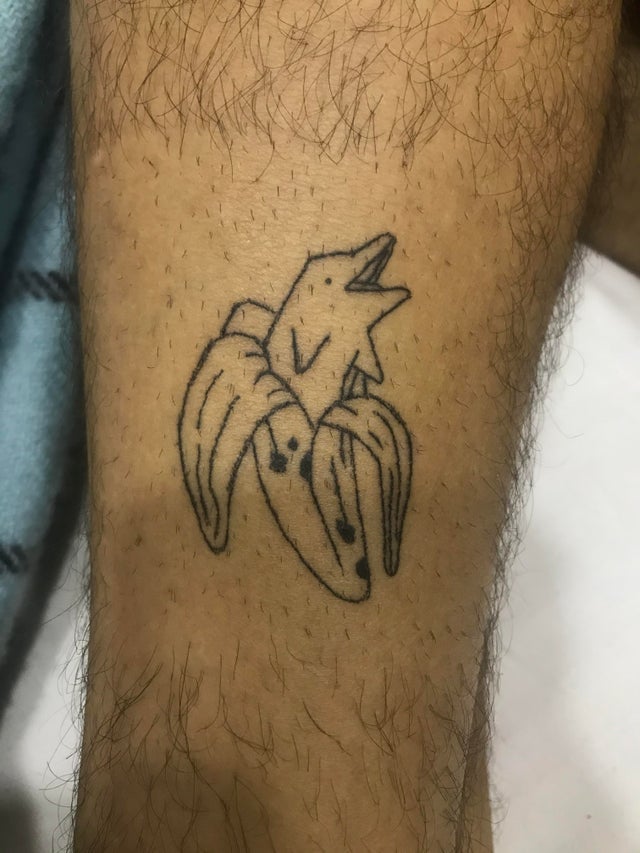 A happy dolphin leaps out of a banana in this funny hand poke tattoo
