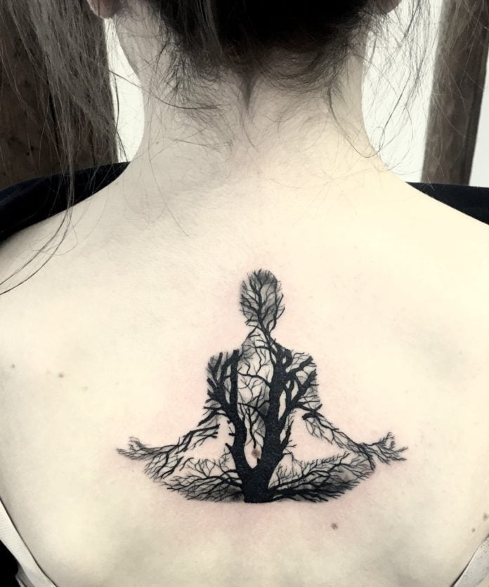 This fantastic back tattoo uses vein-like tree branches to reveal the form of a woman sitting and meditating. 