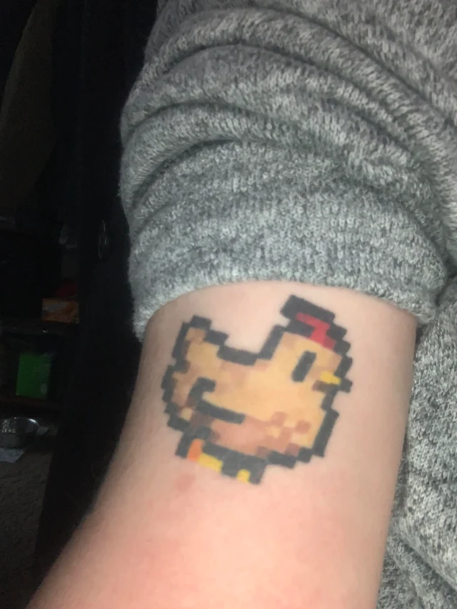 This Stardew Valley tattoo shows a Void Chicken, coloured with cheerful yellow inks