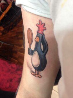 This fun chicken tattoo features Feathers McGraw, the sinister but lovable chicken character from the stop motion film franchise Wallace and Gromit. The tattoo artist has chosen to create a cartoon style design of this cheeky chicken but it still retains the soft quality of the clay that Feathers McGraw is made out of in the stop motion movies.